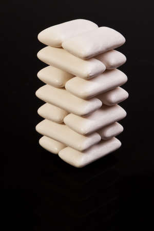 Stacked white spearmint chewing gums isolated over back background.の写真素材