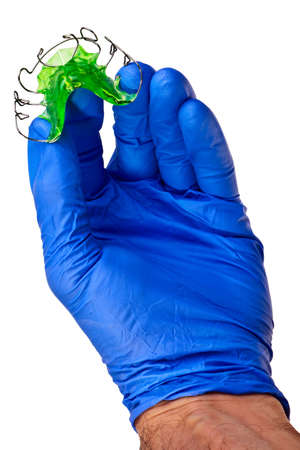 Orthodontic correction apparatus hold by male hand in blue latex glove.の写真素材