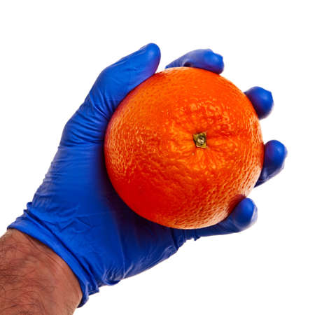 Big fresh orange held in male hand in blue latex glove.の写真素材
