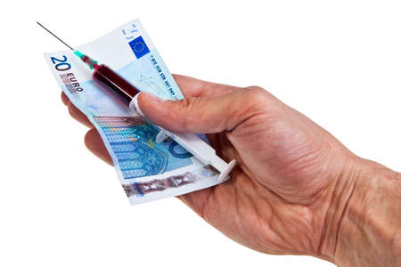 Syringe with red liquid and 20 Euro banknote hold by caucasian male hand over white background.の写真素材