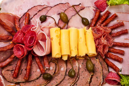 Dish with sliced ham, cheese, salami rolls and lettuce closeup view.の写真素材