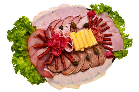 Dish with sliced ham, cheese and salami rolls and lettuce isolated over white background.