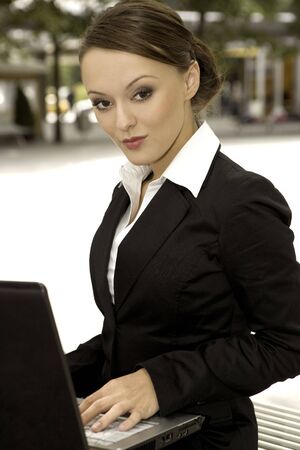 young and attractive brunette businesswoman working on laptop outdoorsの写真素材