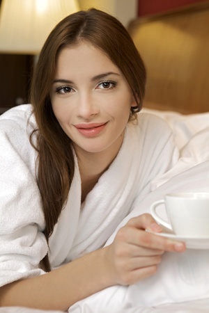 Closeup portrait of a happy young beautiful woman with a white cupの写真素材