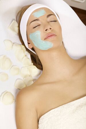 young woman getting beauty skin mask treatment on her face with brushの写真素材