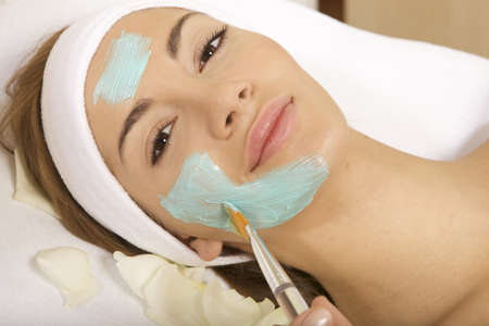 young woman getting beauty skin mask treatment on her face with brushの写真素材