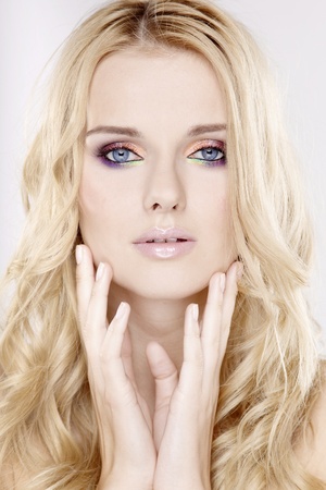 Young pretty woman with beautiful blond hairs and multicolor makeup isolated on white backgroundの写真素材
