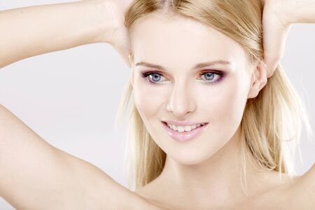 Young pretty woman with beautiful blond hairs and multicolor makeup isolated on white backgroundの写真素材