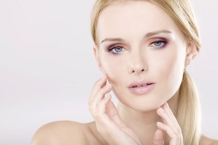 Young pretty woman with beautiful blond hairs and multicolor makeup isolated on white backgroundの写真素材