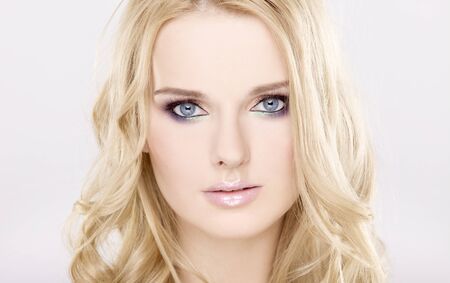 Young pretty woman with beautiful blond hairs and multicolor makeup isolated on white backgroundの写真素材