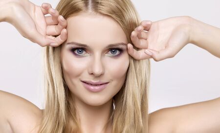 Young pretty woman with beautiful blond hairs and multicolor makeup isolated on white backgroundの写真素材