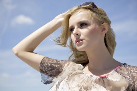 portrait of beautiful blonde girl in sunglasses on background blue skyの写真素材