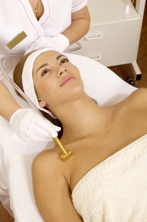 Young brunette woman receiving laser therapy. Spa studio shotの写真素材