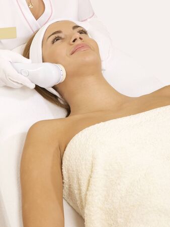 Young brunette woman receiving laser therapy. Spa studio shotの写真素材