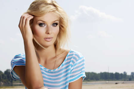 portrait of beautiful blonde girl on background blue skyの写真素材