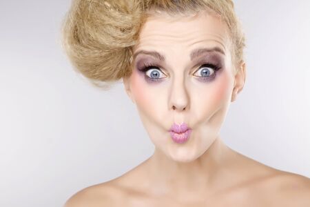 Young pretty woman with beautiful blond hairs and multicolor makeup isolated on white backgroundの写真素材