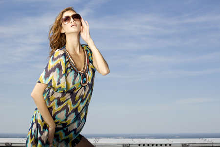 portrait of beautiful brunette girl in sunglasses on background blue skyの写真素材