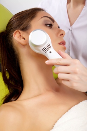 Young brunette woman receiving laser therapy. Spa studio shotの写真素材