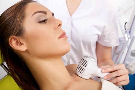 Portrait of attractive beautiful young adult brunette woman having a stimulating facial treatment from a therapist on the table in proffessional clinic spaの写真素材