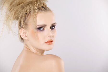 Young pretty woman with beautiful blond hairs and multicolor makeup isolated on white backgroundの写真素材