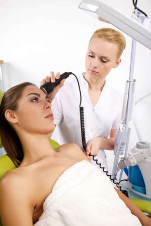 Young brunette woman receiving laser therapy. Spa studio shotの写真素材