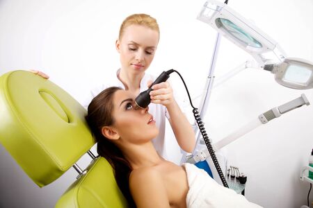 Young brunette woman receiving laser therapy. Spa studio shotの写真素材