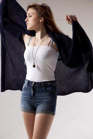 portrait of a beautiful young  brunette woman in blue sweater dress and jeans short on greybackground. Autumn style the fashionの写真素材