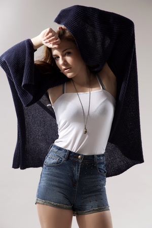 portrait of a beautiful young  brunette woman in blue sweater dress and jeans short on greybackground. Autumn style the fashionの写真素材