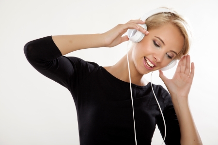 Beautiful adult sensuality young adult blonde girl is listen to the music in white headphonesの写真素材