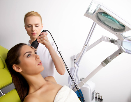 Young brunette woman receiving laser therapy. Spa studio shotの写真素材