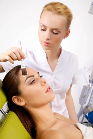 young woman getting beauty skin mask treatment on her face with brushの写真素材