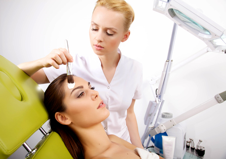 young woman getting beauty skin mask treatment on her face with brushの写真素材