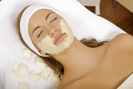 young woman getting beauty skin mask treatment on her face with brushの写真素材