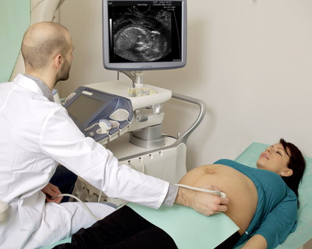 Pregnant woman getting ultrasound from doctor in hospitalの写真素材
