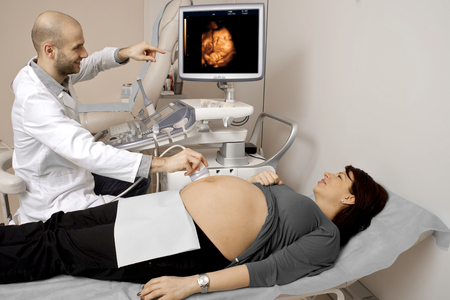 Pregnant woman getting ultrasound from doctor in hospitalの写真素材