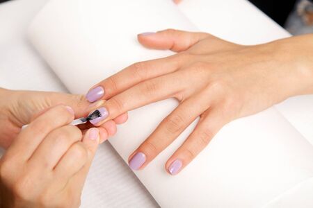 Manicure - Beautiful manicured woman's nails with violetnail polish on soft white towel.の写真素材