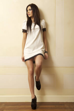Beautiful and attractive young adult female brunette sensuality woman posing in white dress in apartmentの写真素材