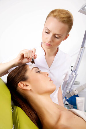 young woman getting beauty skin mask treatment on her face with brushの写真素材