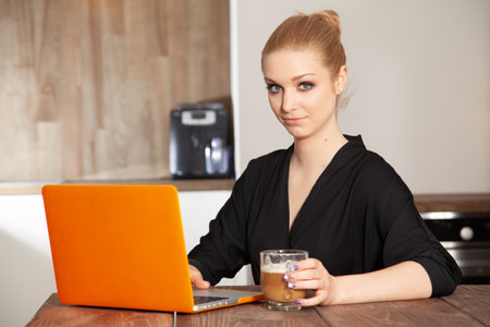 Portrait of a attractive young adult pretty blond student girl working on the orange computerの写真素材
