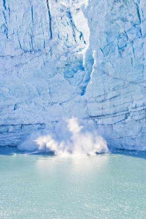 Glacier drops chunks of ice and snow into the ocean の写真素材