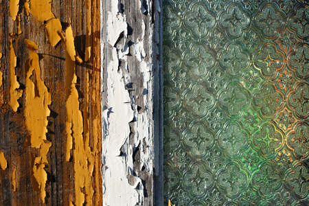 A close-up picture of an old wooden house window with pealing off paint and old decorated window glassの写真素材