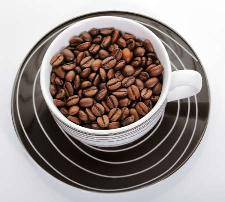 A cup full of coffee beans on a white の写真素材