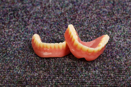 A set of dentures laying on a dark gray carpetの写真素材