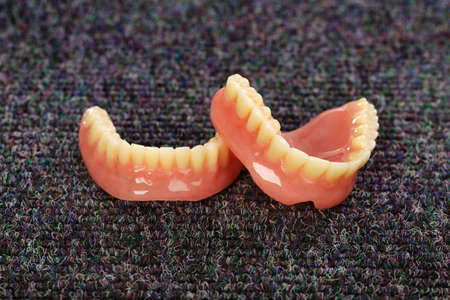A set of dentures laying on a dark gray carpetの写真素材
