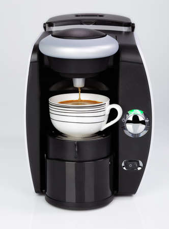 A black modern espresso coffee machine is making a coffee on a white backgroundの写真素材