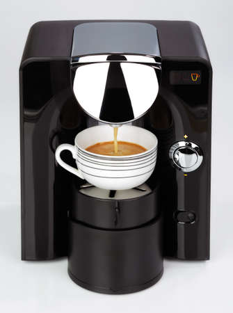 A black modern espresso coffee machine is making a coffee on a white backgroundの写真素材