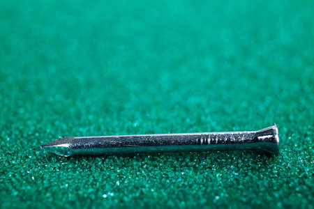 A macro image of enforced concrete nail on a green sandpaperの写真素材