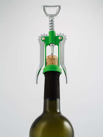 Green and chrome corkscrew wine opener with wine bottle on white backgroundの写真素材