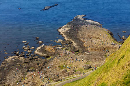Thousands of tourists visiting Giant's Causeway in County Antrim of Northern Ireland, a World Heritage Site by UNESCO containing about 40000 interlocking basalt columns from ancient volcanic eruptionのeditorial素材