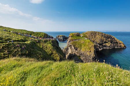 Thousands of tourists visiting Carrick-a-Rede Rope Bridge in County Antrim of Northern Ireland, hanging 30m above rocks and spanning 20m, linking mainland with the tiny island of Carrickaredeのeditorial素材